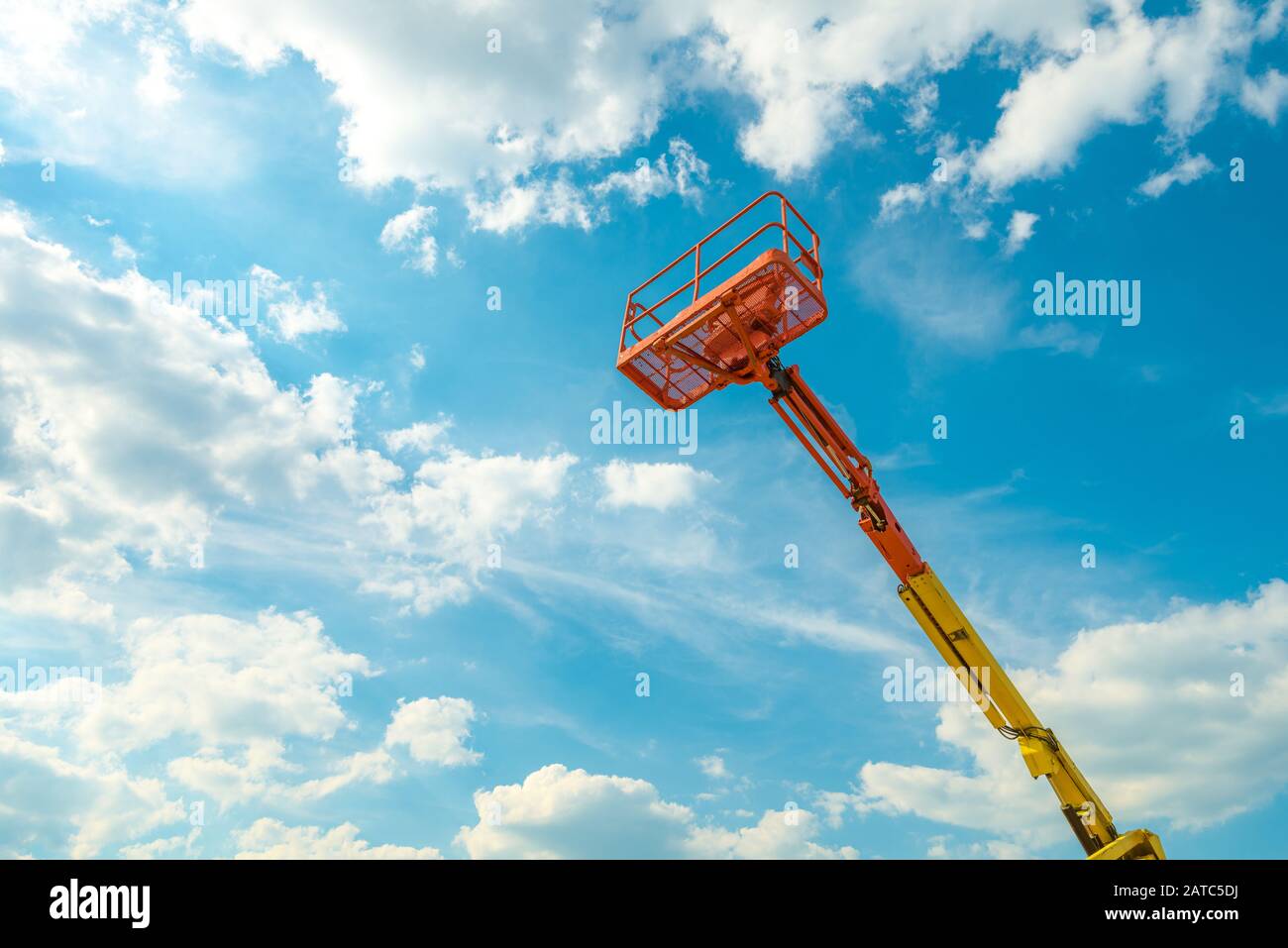 Cherry picker on the blue sky background. Boom with lift bucket of heavy machinery. View of the platform of the telescopic construction lift in summer Stock Photo