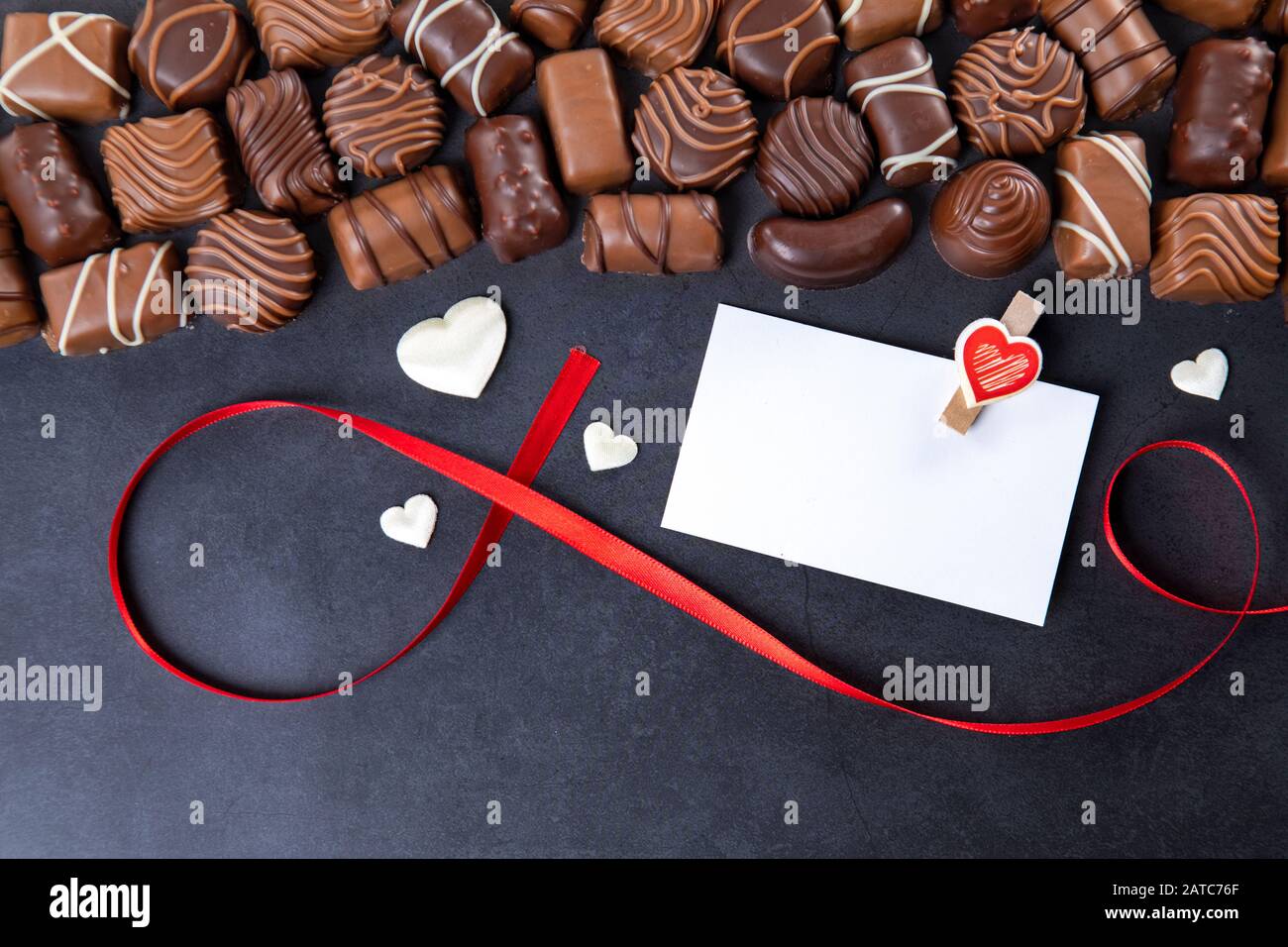 Chocolate pralines with white card for Valentines day on black background Stock Photo