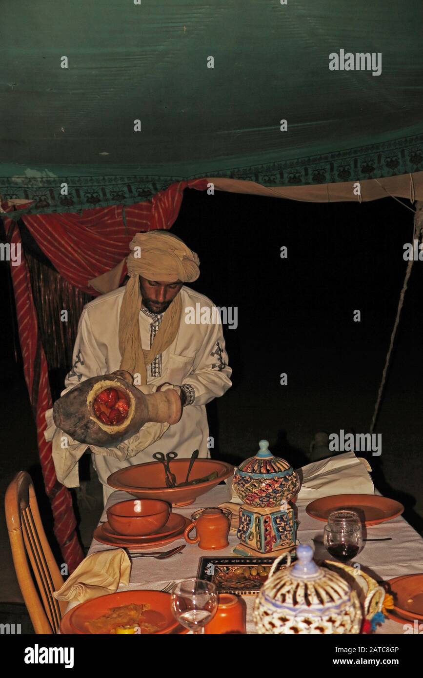 Chef serving food in the camp restaurant from a traditional clay pot