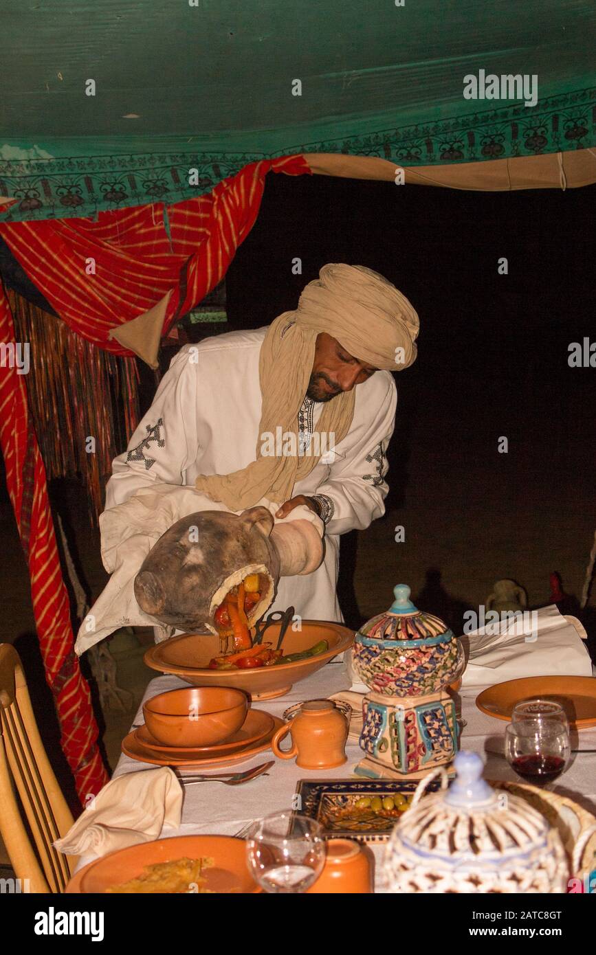 Chef serving food in the camp restaurant from a traditional clay pot