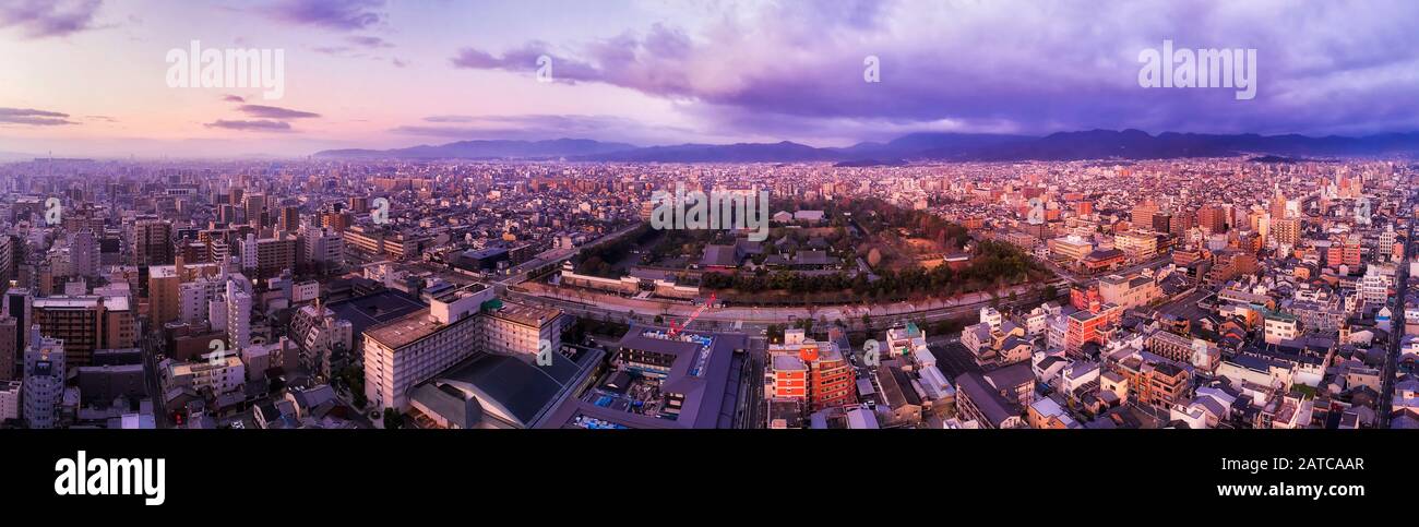 WIde aerial panorama over Kyoto city at sunrise from distant Kyoto tower to mountain ranges and historic castle. Stock Photo