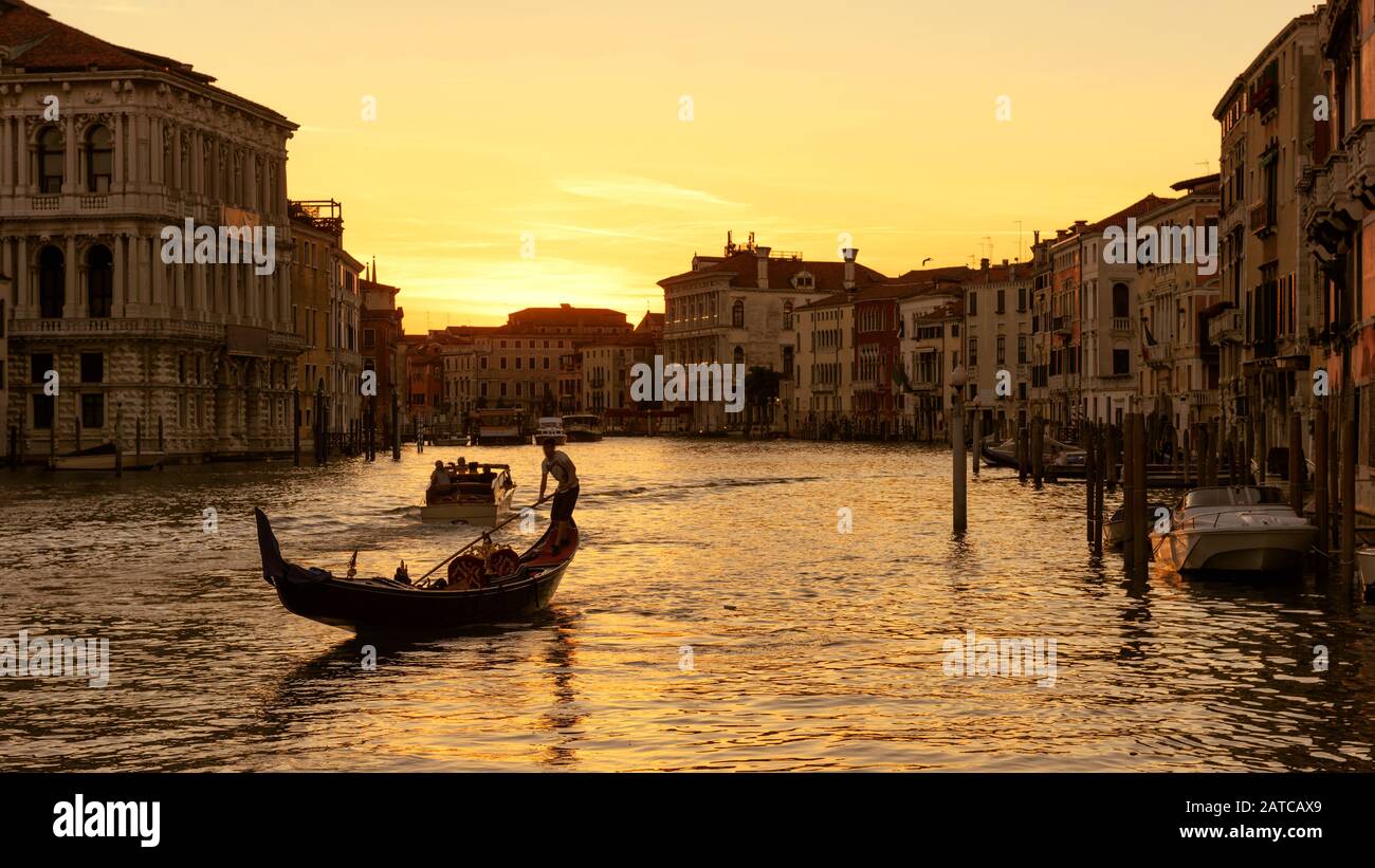 Grand Canal with gondola and motor boats at sunset in Venice, Italy. Grand Canal is one of the major water-traffic corridors and tourist attraction in Stock Photo
