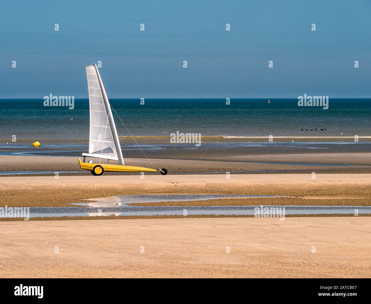 Sand sailing at an empty beach and people exercising in cold water in Bray-Dunes Stock Photo