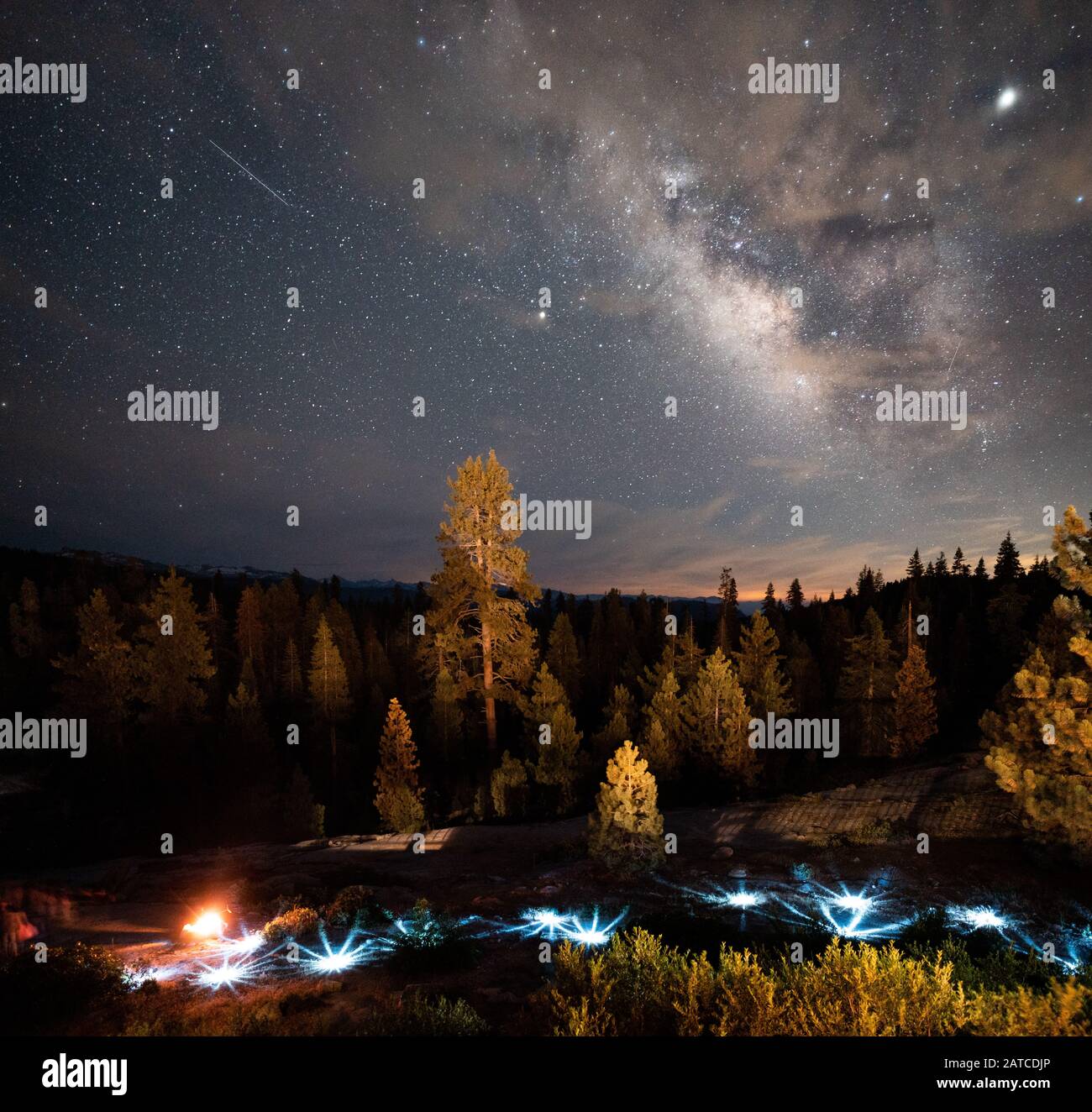Milky Way and Shooting Star over Festive Lights and a campfire, Kings Canyon, Sequoia National Park, California, USA Stock Photo