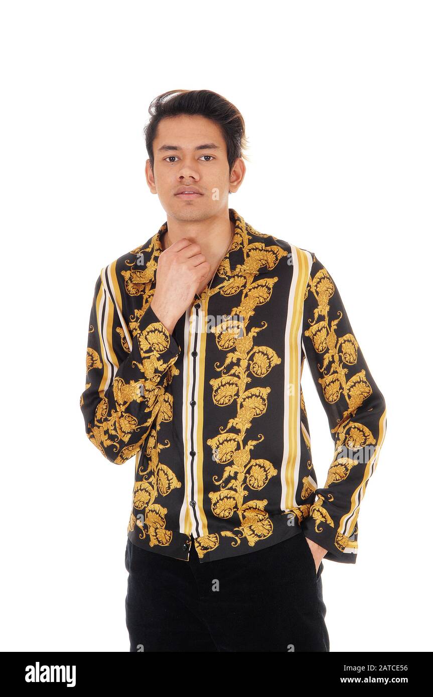 A young handsome man standing in the studio in a gold colored shirt and ...