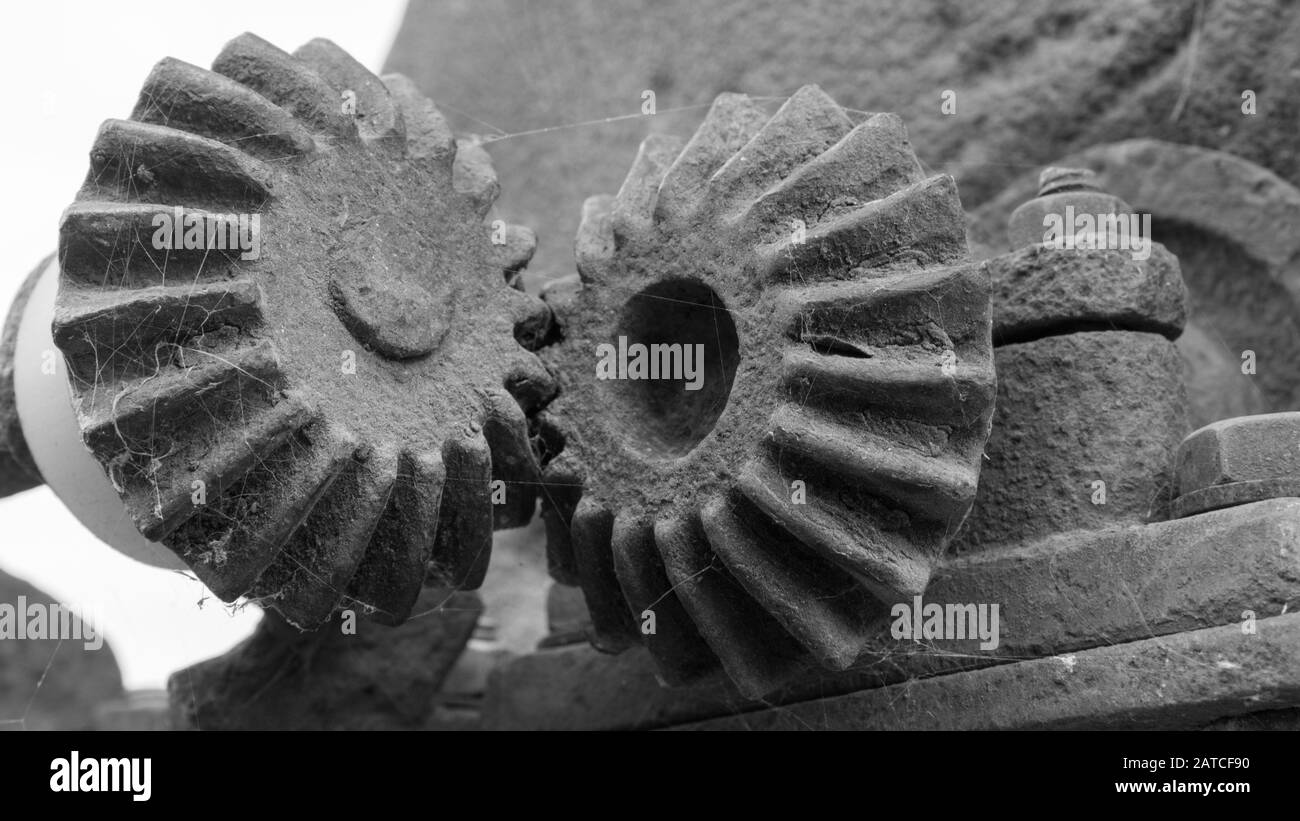 Two old stone gears with cobwebs that mesh Stock Photo