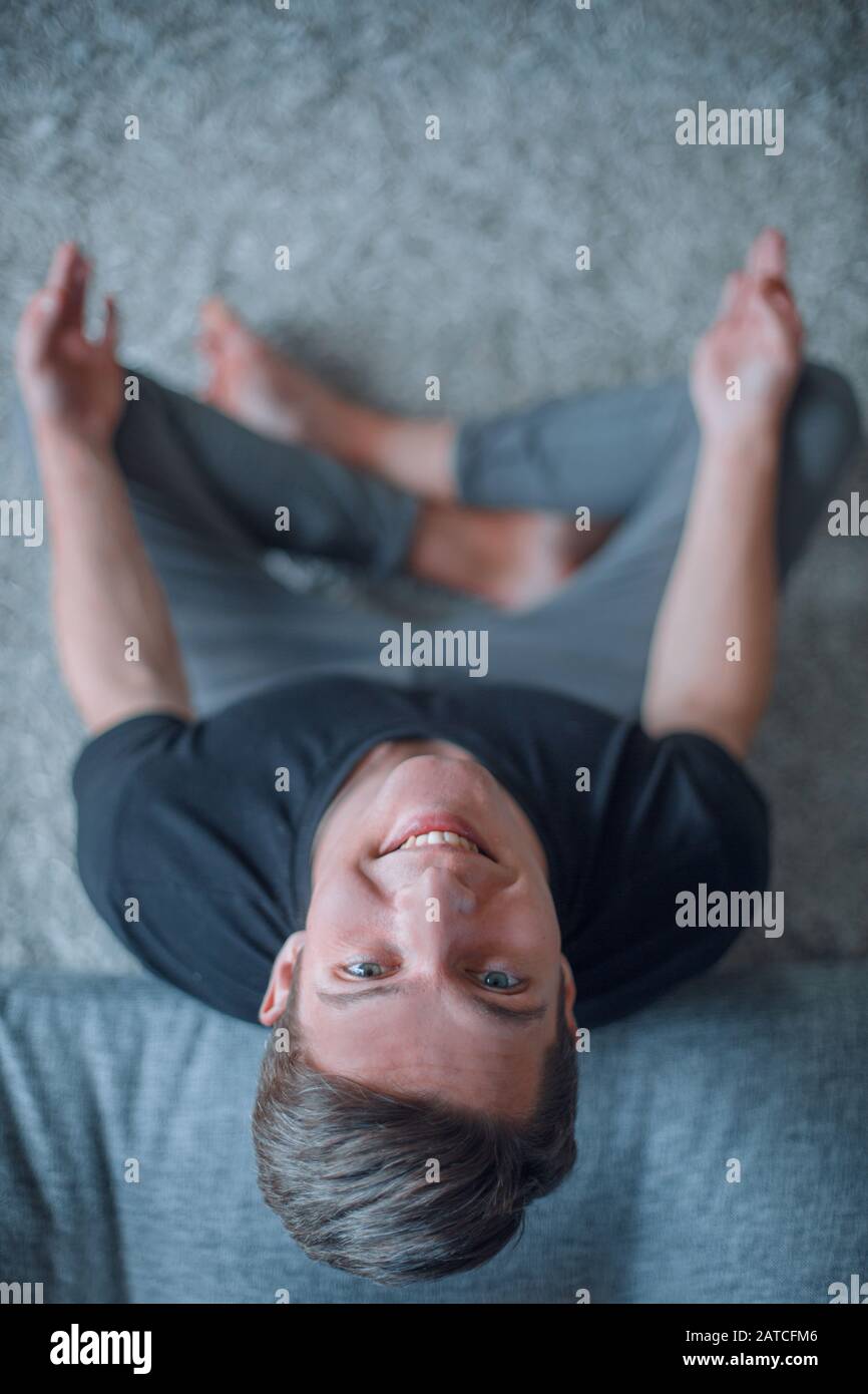 smiling young man sitting on the floor and looking at the camera Stock ...