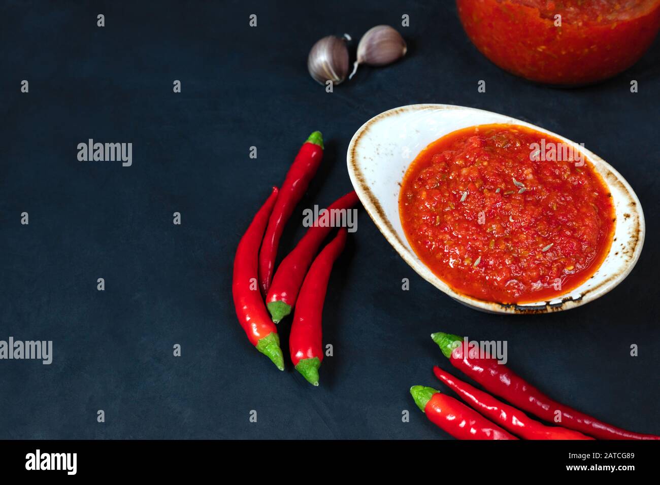 Hot chili pepper sauce paste harissa. Adjika on a blue background. Traditional Tunisia,