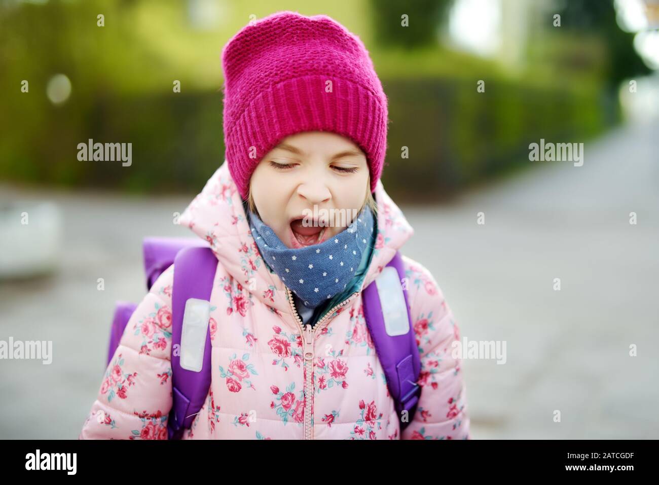 Cute sleepy little girl yawning on her way to school. Child with a backpack in a morning. Education for kids. Stock Photo