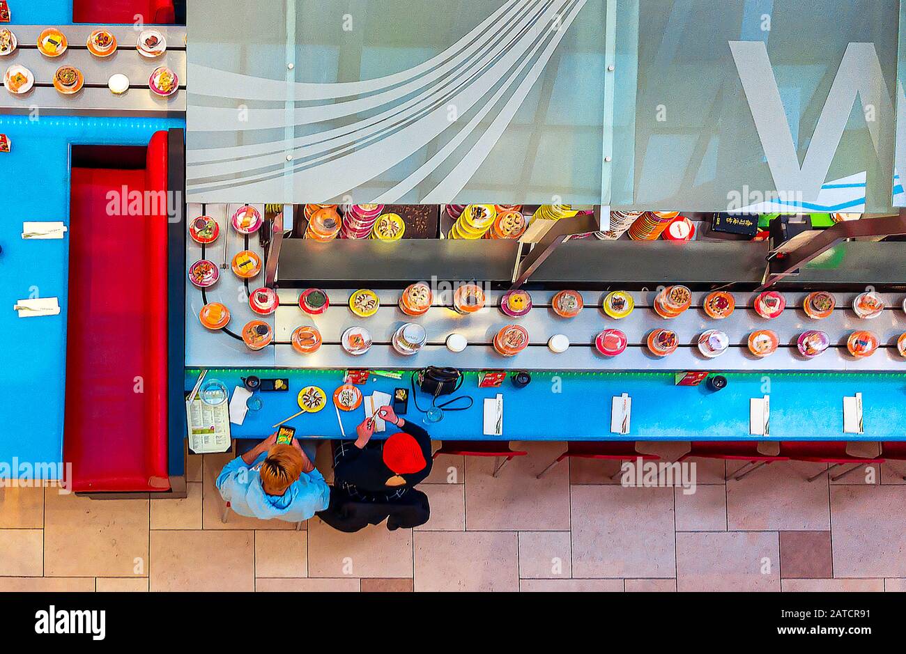 Two friends enjoy a sushi lunch in a conveyer belt restaurant Stock Photo