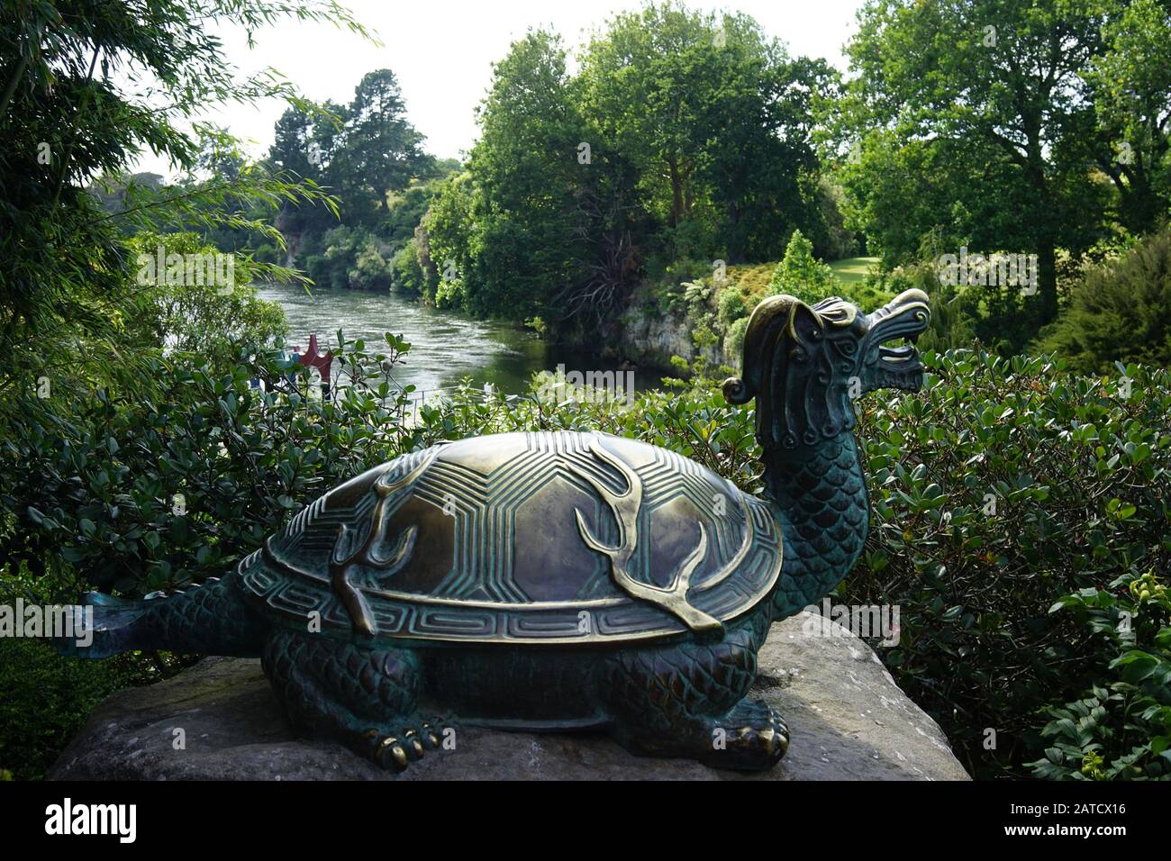 Beautiful statue of a dragon-turtle on a stone near the bank of a river in the park Stock Photo