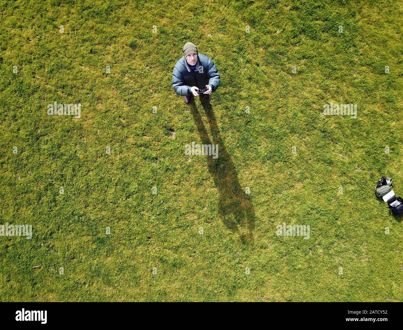 Man looking up while flying a drone with a green grass background. Victoria, Australia. Stock Photo