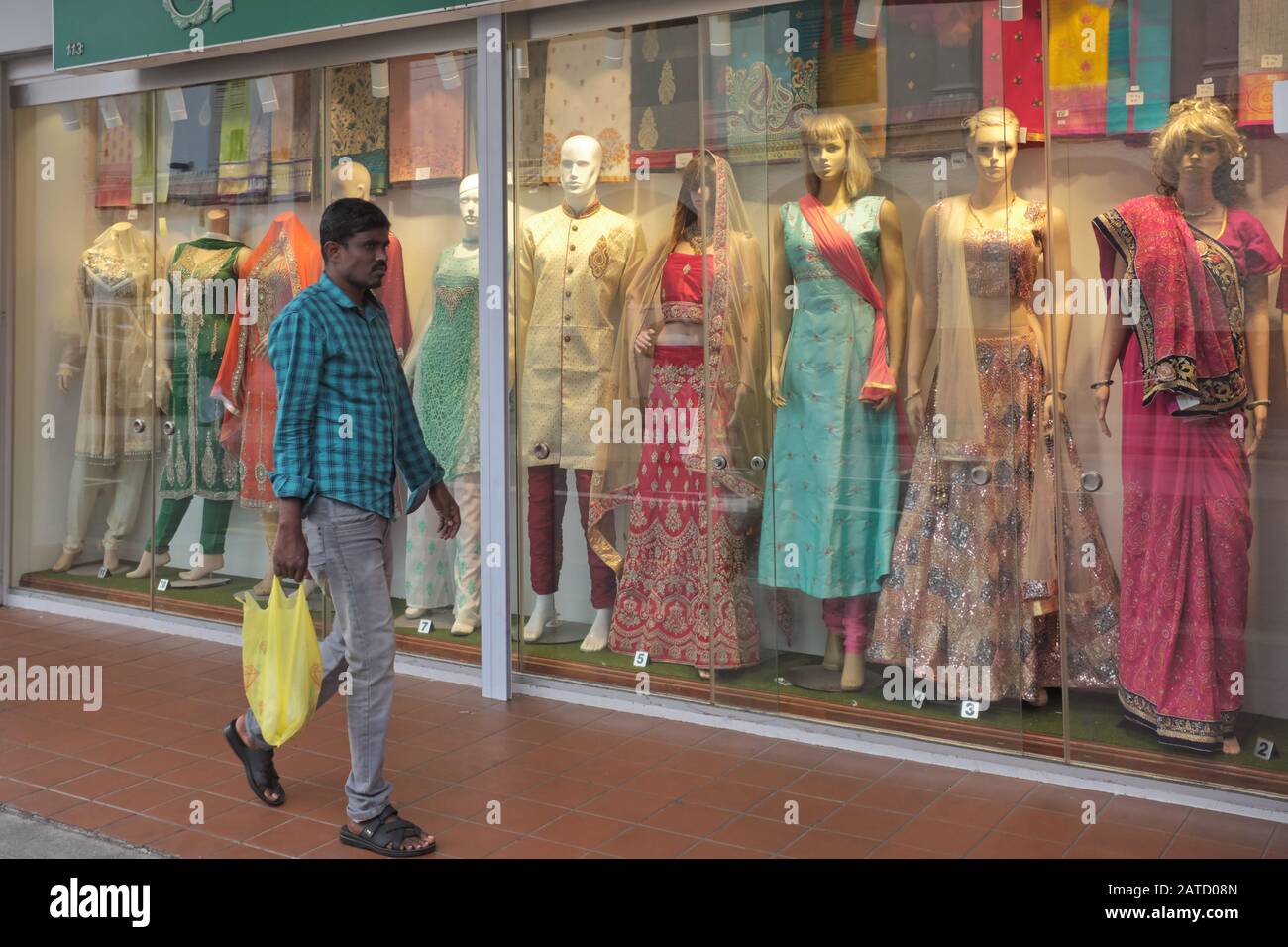 An Indian guest worker passes by a shop selling Indian traditional attire; Little India area, Singapore Stock Photo