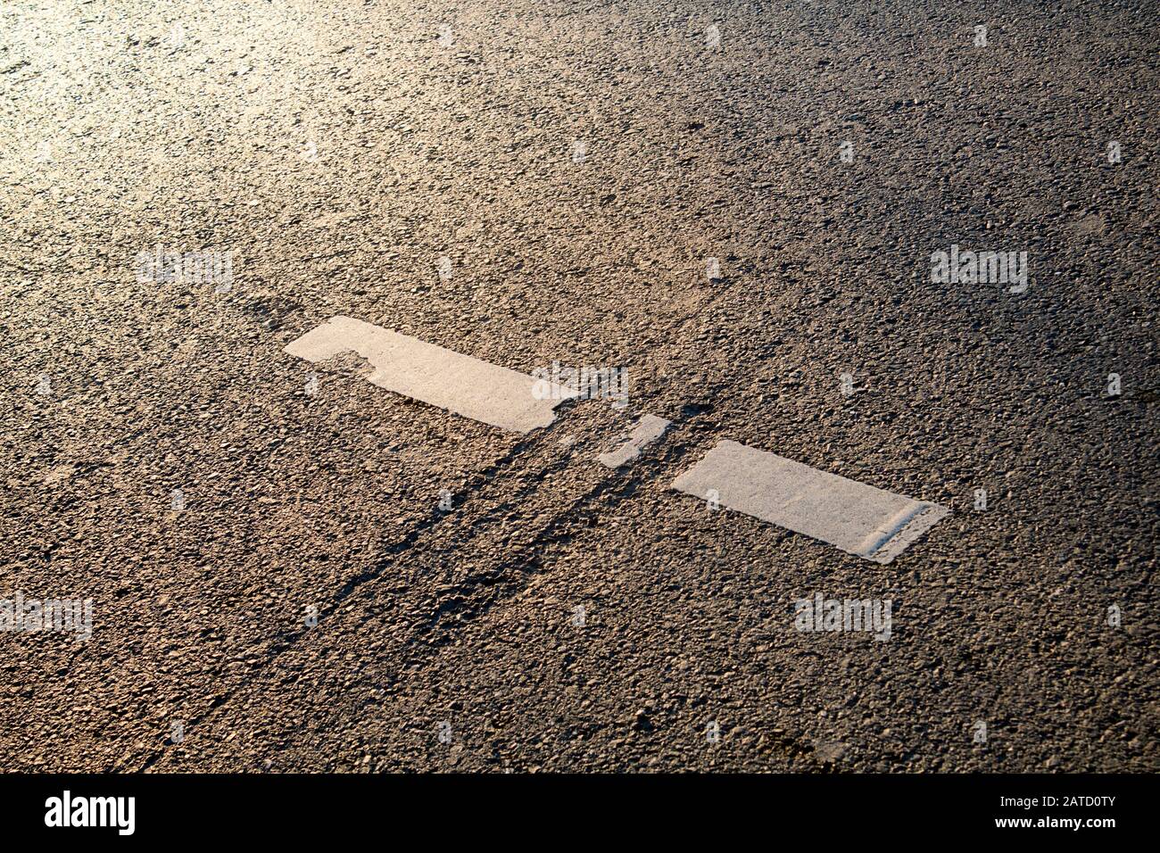 Close up of a scar on asphalt road, dividing a thermoplastic road mark,  reminding a jurassic attack. Highway policy, upkeep, maintenance concepts. Stock Photo