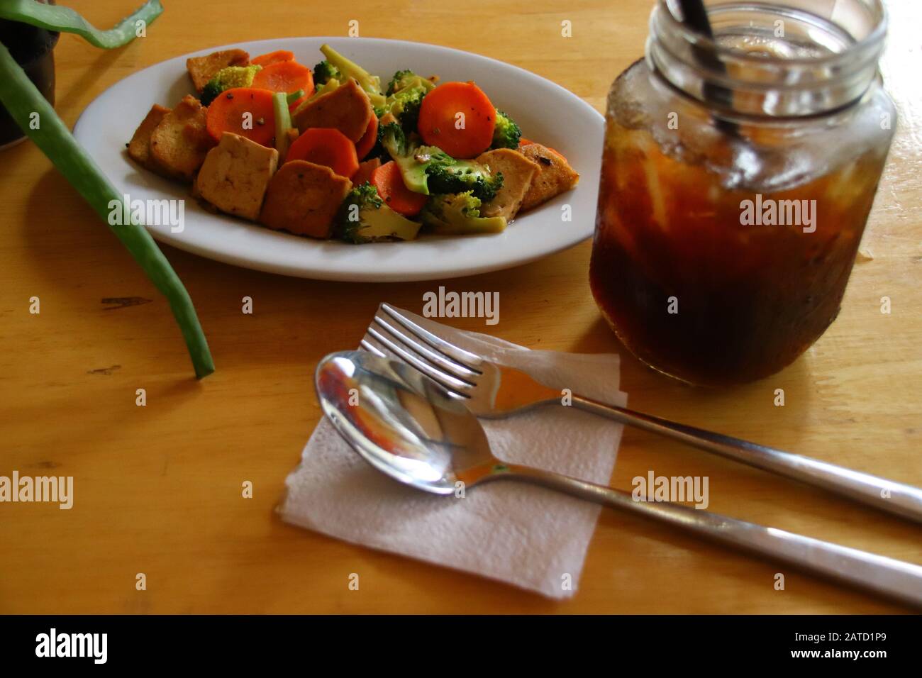 Overhead view of stir-fried tofu and vegetables and iced coffee, healthy plant-based vegan meal Stock Photo