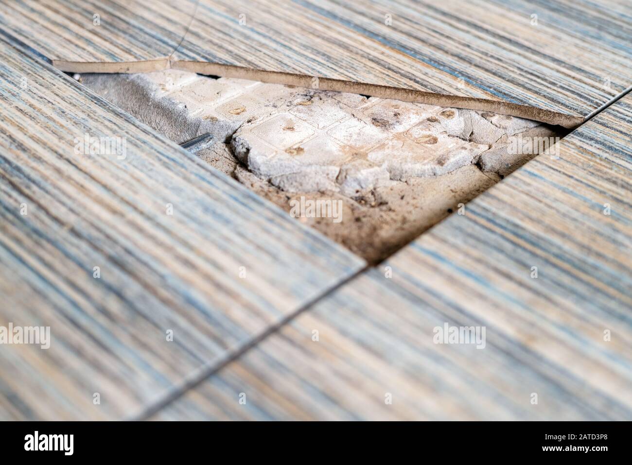Close up view of broken tile in the bathroom. Cracked asbestos floor tile. Damaged ceramic tile background Stock Photo