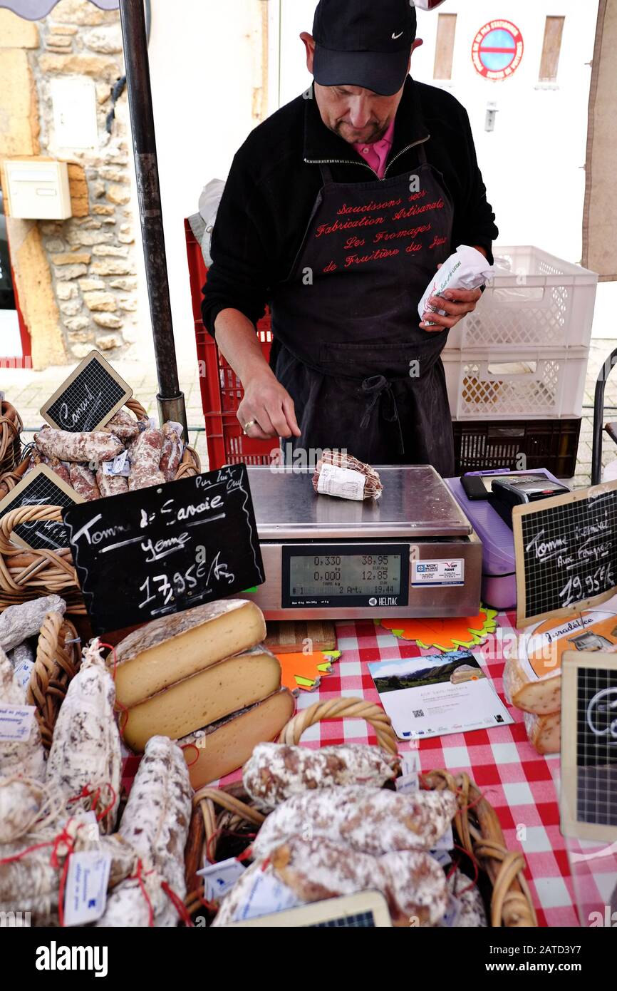 Weighing a  piece of saucisson at the local producers for sale at the outdoor French street market in Le Bois-d'Oingt Stock Photo