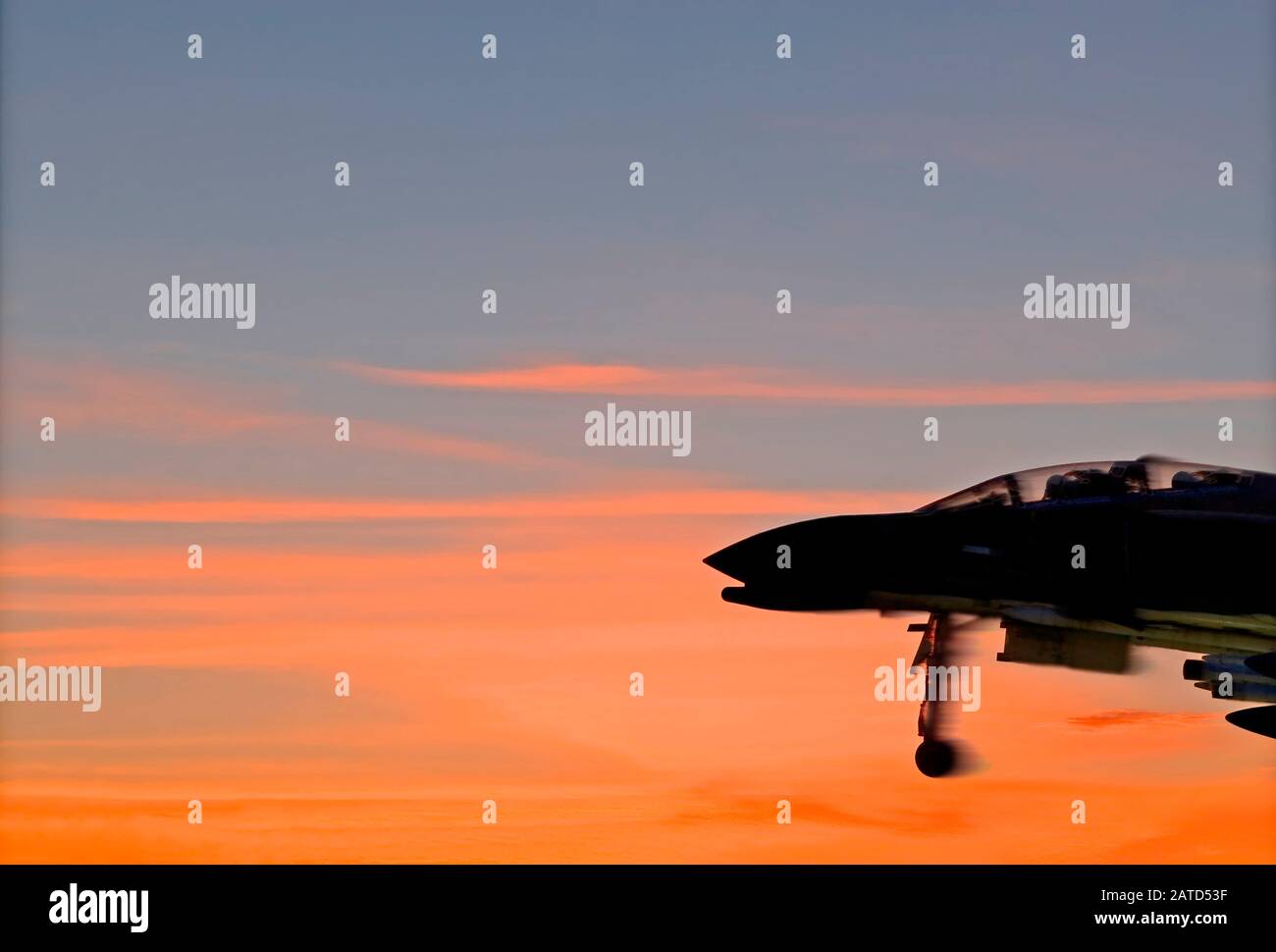 Silhouette of a historic McDonnell Douglas F-4 Phantom II fighter jet taking off against the red clouds of the morning sky over Mobile Bay, Alabama. Stock Photo