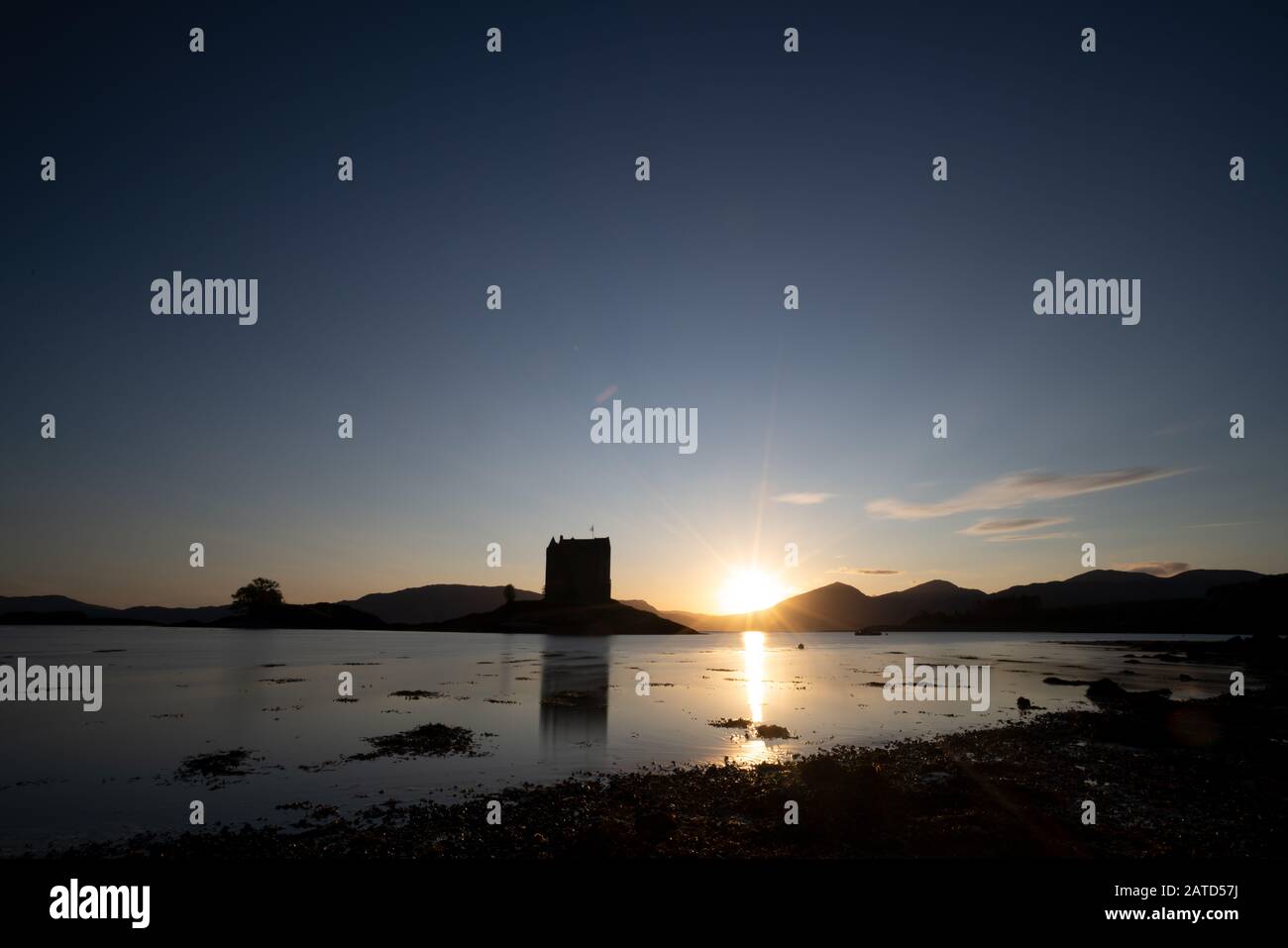 Sunset over Castle Stalker is a four storey tower house or keep picturesquely set on a tidal islet on Loch Laich, an inlet off Loch Linnhe. It is abou Stock Photo