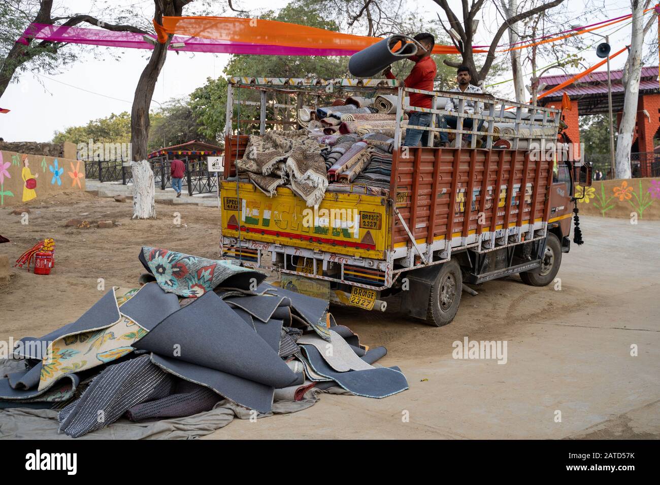 Faridabad, India - Febuary 1, 2020: Vendors toss rugs out of a truck, for sale to set up at their booth at the Surajkund Crafts Mela Stock Photo