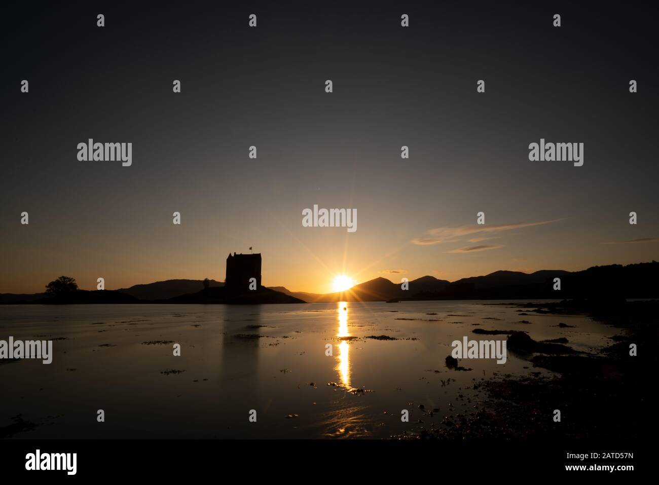 Sunset over Castle Stalker is a four storey tower house or keep picturesquely set on a tidal islet on Loch Laich, an inlet off Loch Linnhe. It is abou Stock Photo