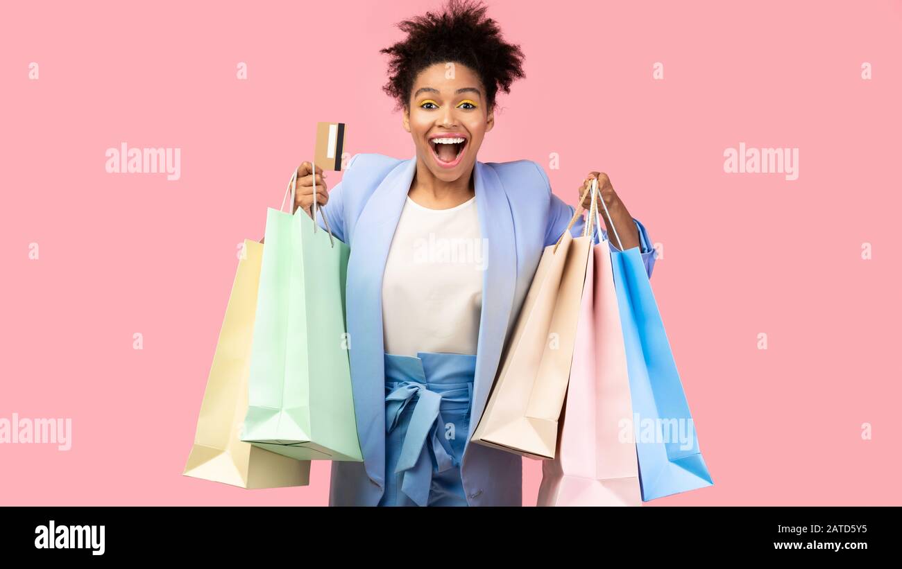 Cheerful black woman with shopping bags and plastic card Stock Photo