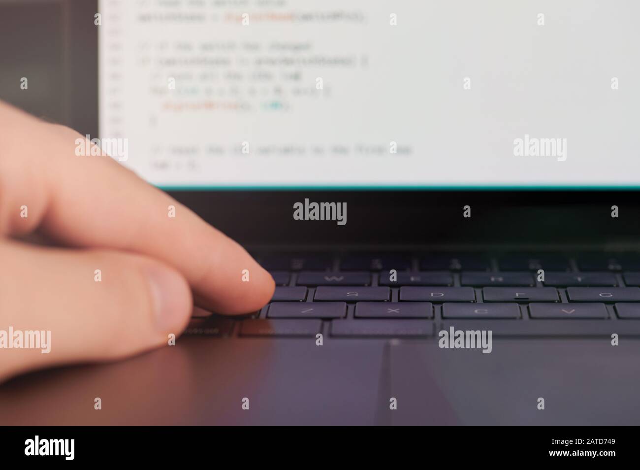 Macro of hand on laptop keyboard typing computer code Stock Photo