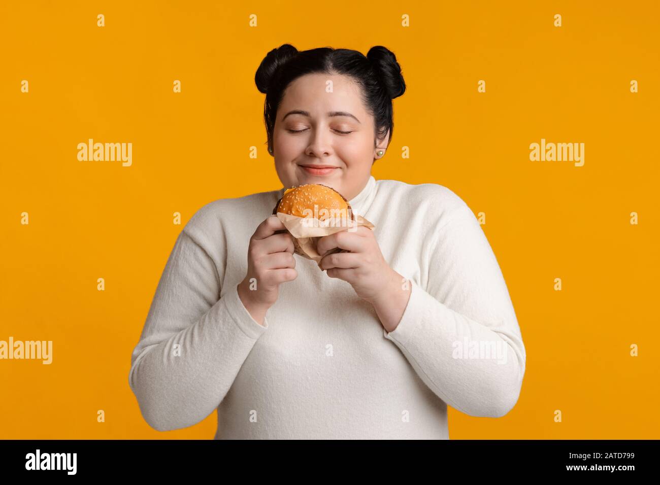 Plump Hungry Girl Holding Burger In Hands And Sniffing It Stock Photo