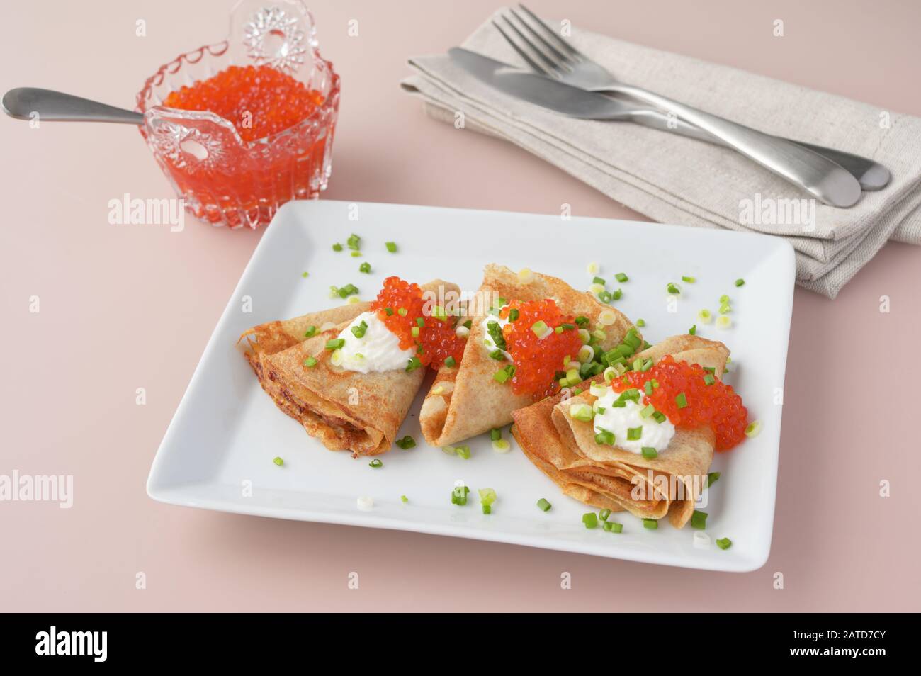 Blinis with red caviar and sour cream decorated with green onion Stock Photo