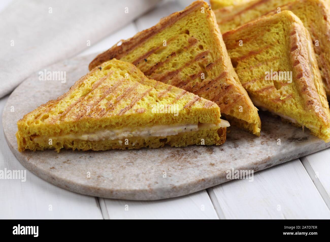 Grilled sandwiches with ham and cheese on a marble cutting board. Toast bread with curcuma gives a bright yellow color Stock Photo