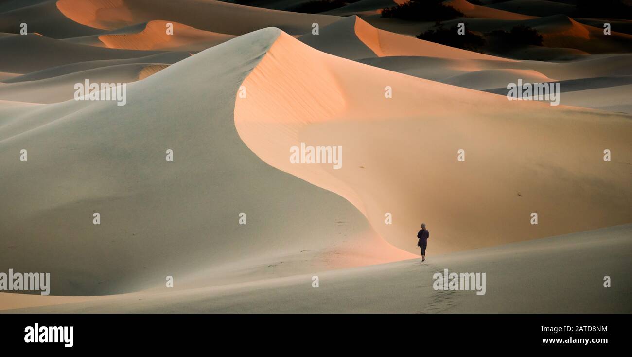 Woman walking in sand dunes, Mesquite Flat Sand Dunes, Death Valley, California, USA Stock Photo