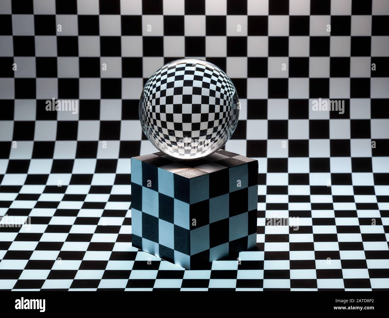 Glass sphere on a cube on a checked background Stock Photo