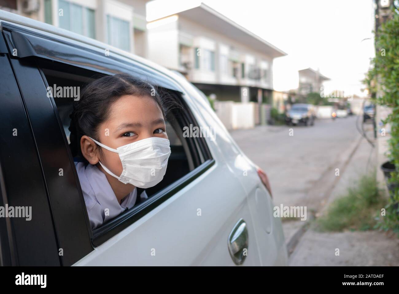 A child wearing a sanitary mask popped his head out of the car window. Stock Photo