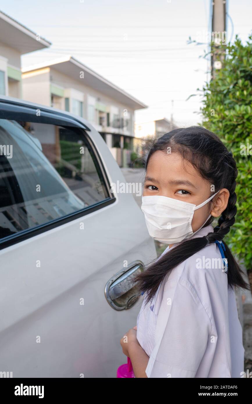 A little Asian girl in a uniform wearing masks when going to school to prevent germs Stock Photo