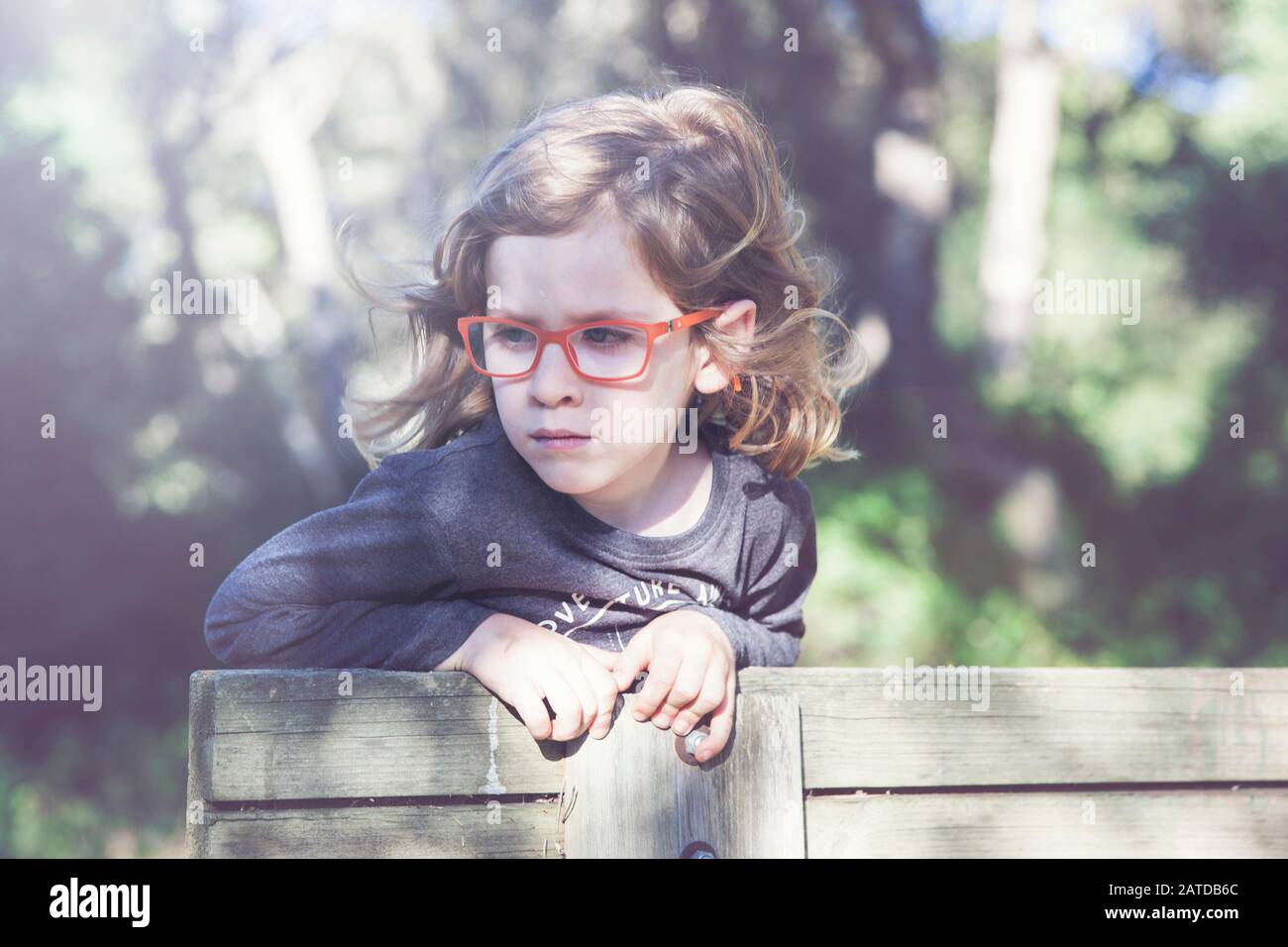 Portrait of a boy wearing spectacles leaning on a fence, Spain Stock Photo