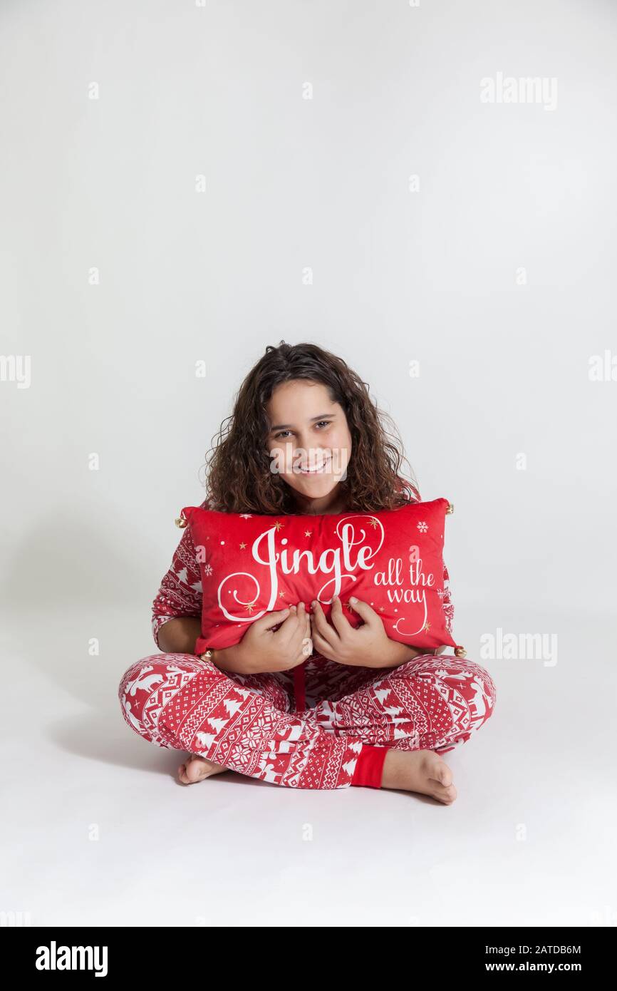 Portrait of a happy girl in pyjamas holding a Christmas pillow Stock Photo