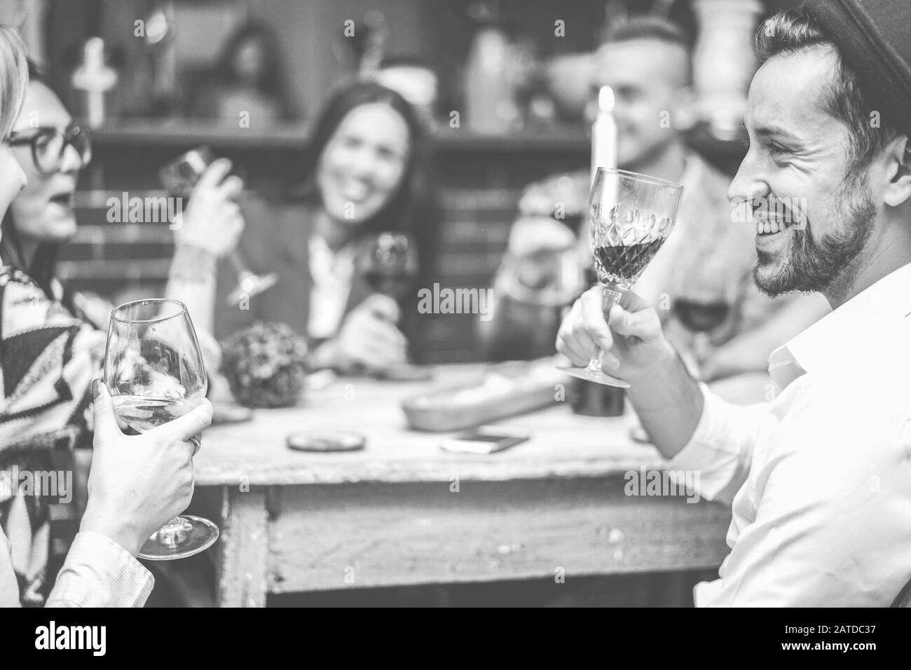 Happy fashion friends toasting wine in trendy cocktail bar restaurant - Young people having fun drinking and laughing together - Focus on right man mo Stock Photo