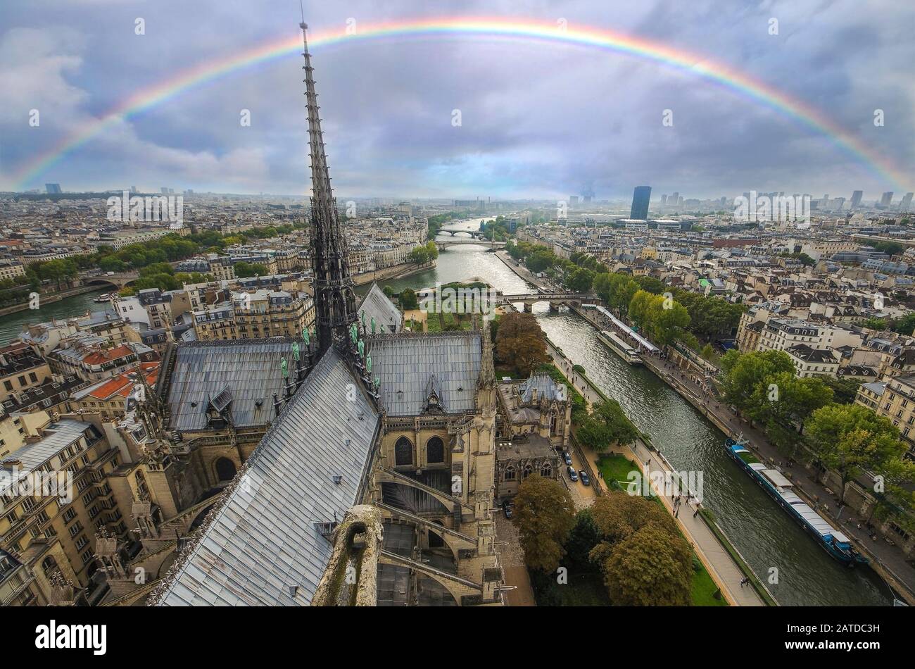 At the top of Cathedral of Notre Dame, Paris, France. View to steeple of church, Seine river, bridges. Cite island with raibow Stock Photo