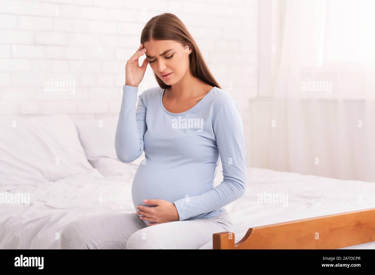 Pregnant Woman Having Headache Feeling Bad Sitting On Bed Indoor Stock Photo