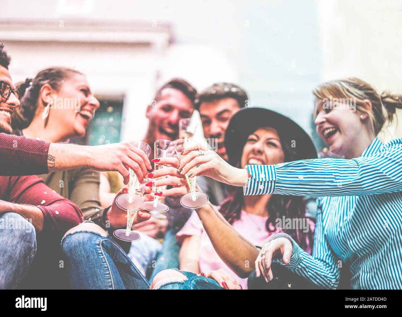 Happy friends cheering with champagne and making party outdoor - Loud fest, fun and drunk concept - Main focus on left man hand - Radial purple and bl Stock Photo