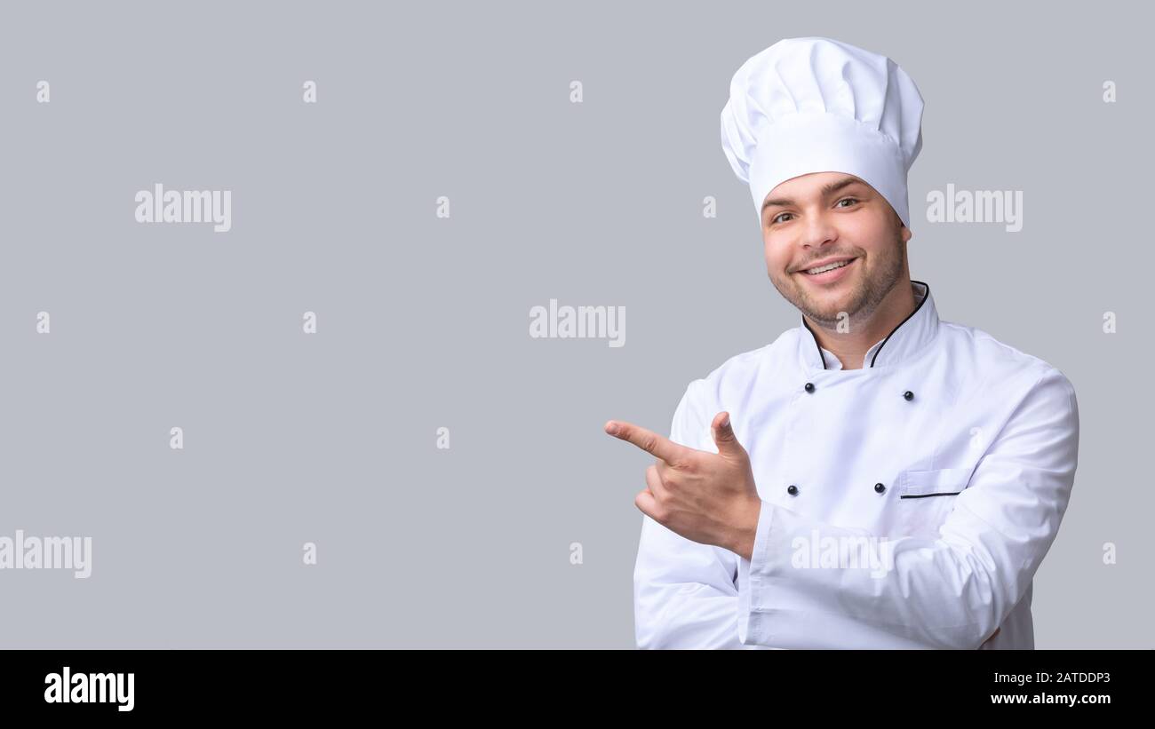 Cook Man Pointing Finger Aside Over Gray Studio Background, Panorama Stock Photo