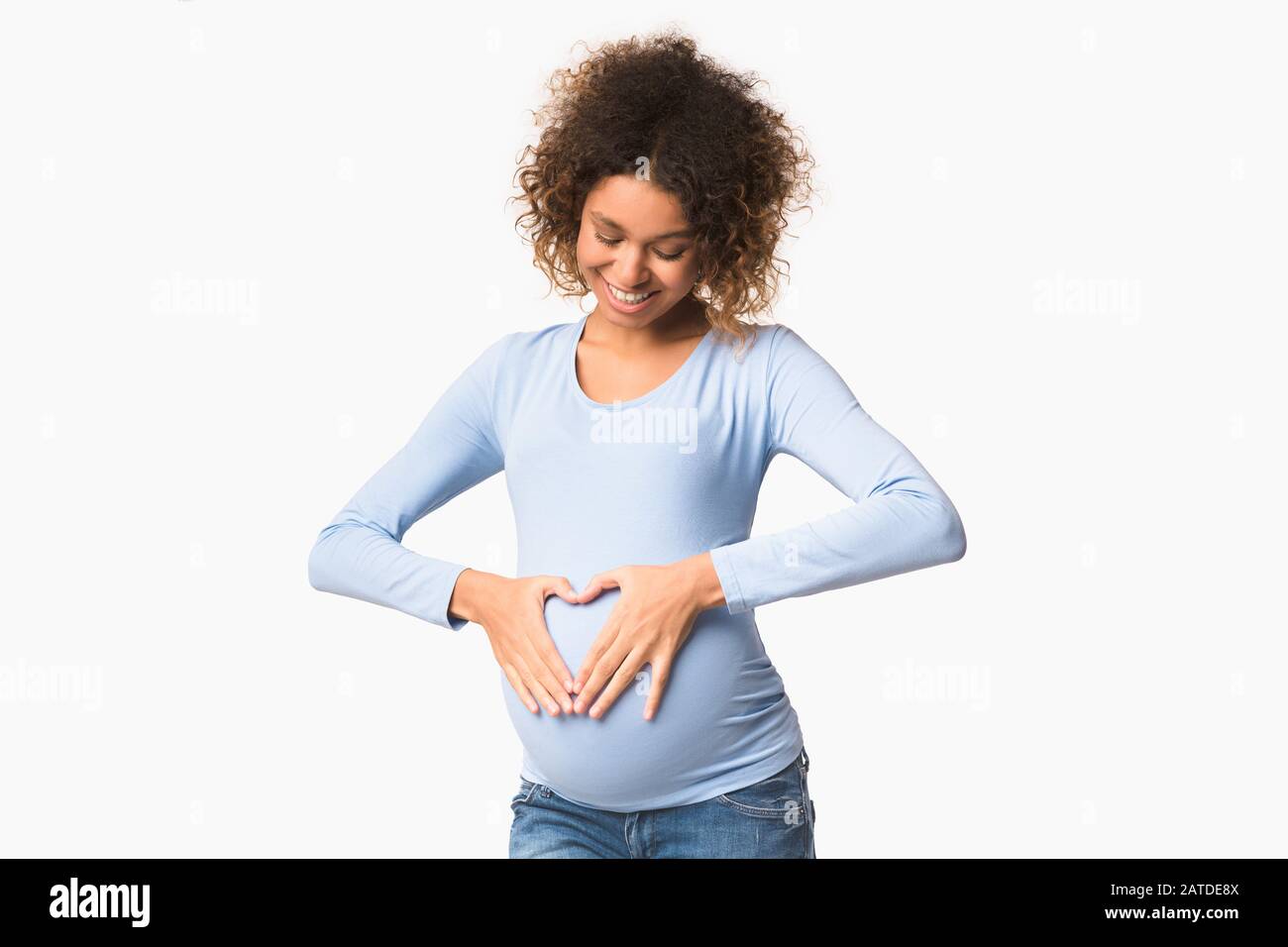Happy expectation. Black pregnant woman forming heart shape on belly Stock Photo
