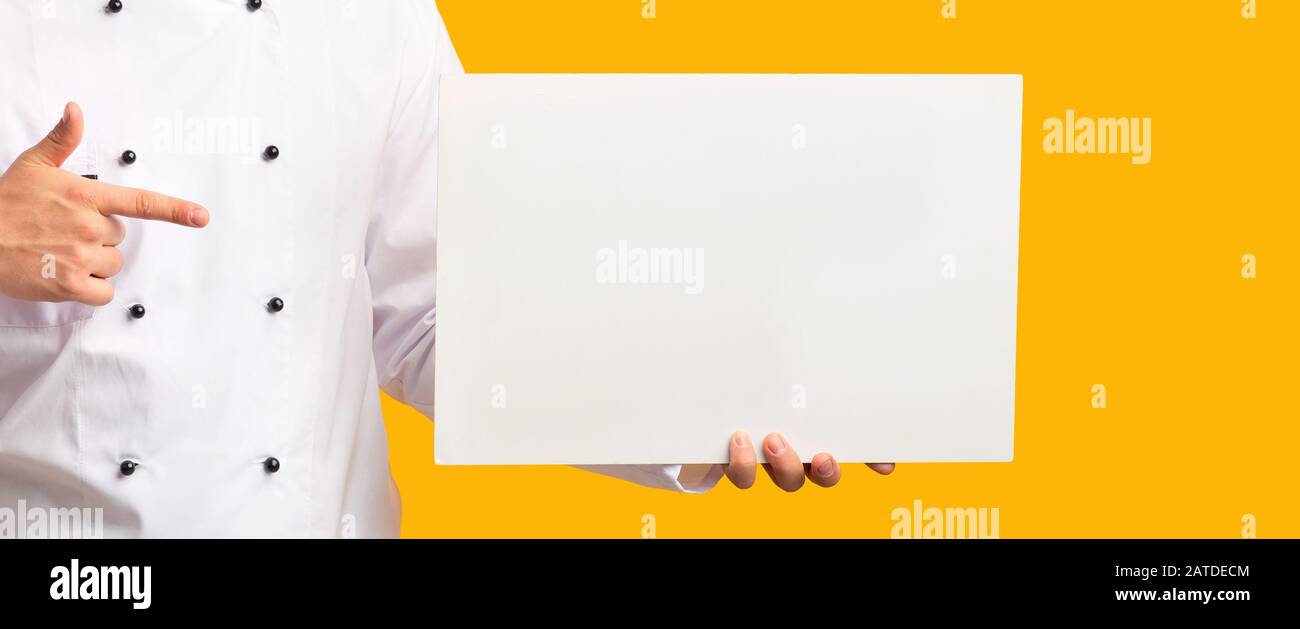 Unrecognizable Chef Showing Blank Poster Over Yellow Background, Panorama, Cropped Stock Photo