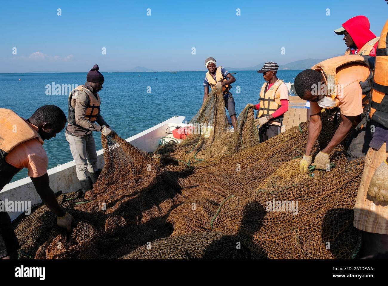 Employees of Victory Farms, the largest fish farmer in Kenya, fix netting for a fish cage in Lake Victoria Stock Photo