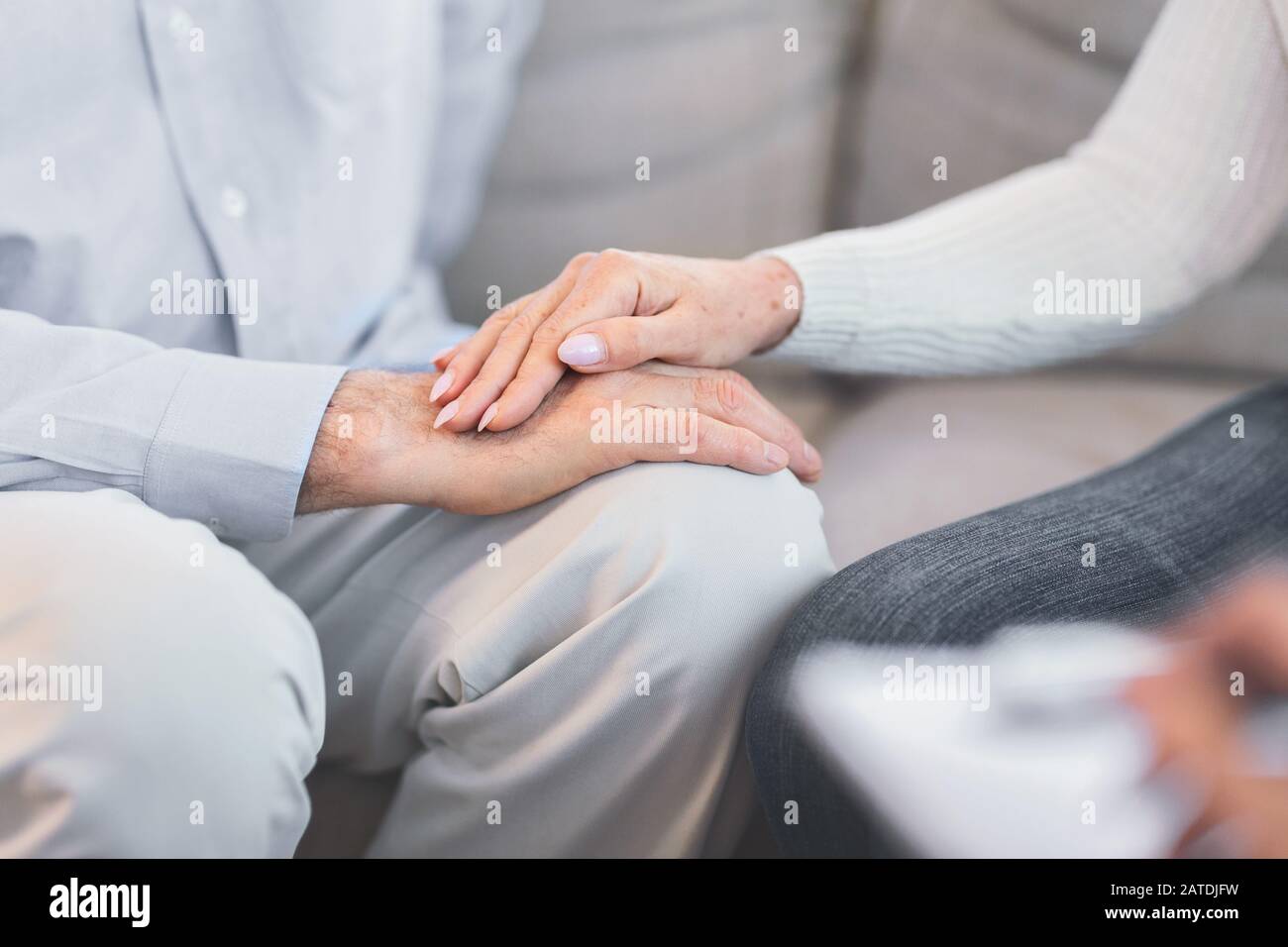 Unrecognizable elderly couple holding hands at session Stock Photo