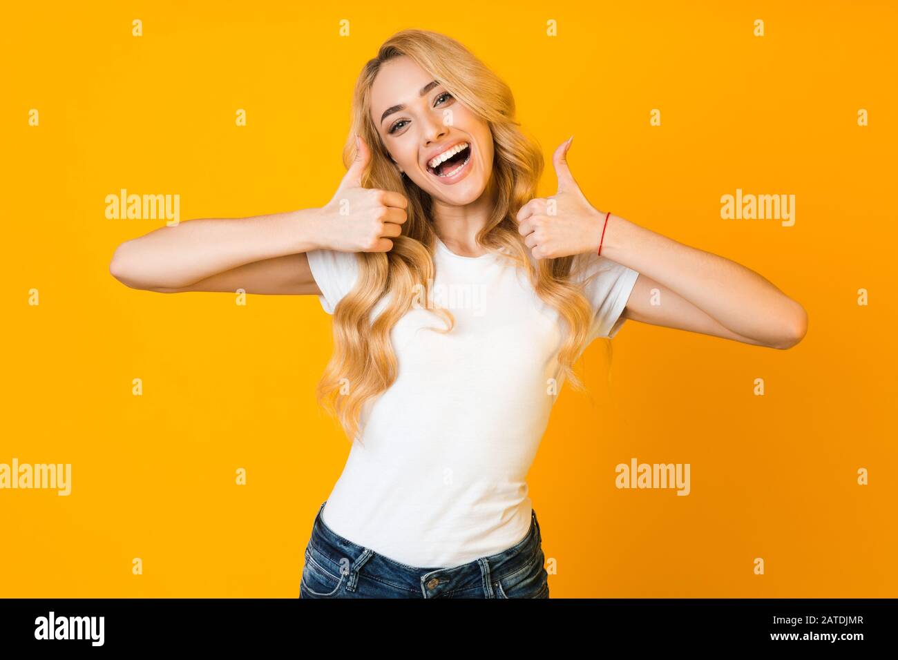 Great news. Girl showing thumbs up and smiling Stock Photo - Alamy