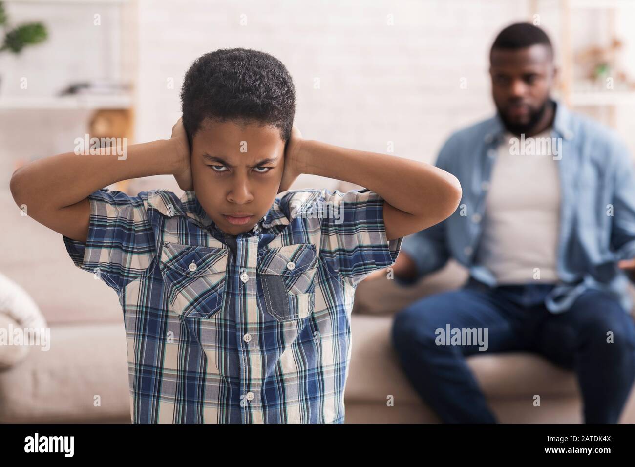 Preteen black boy closing ears not to listen father's scolding Stock Photo