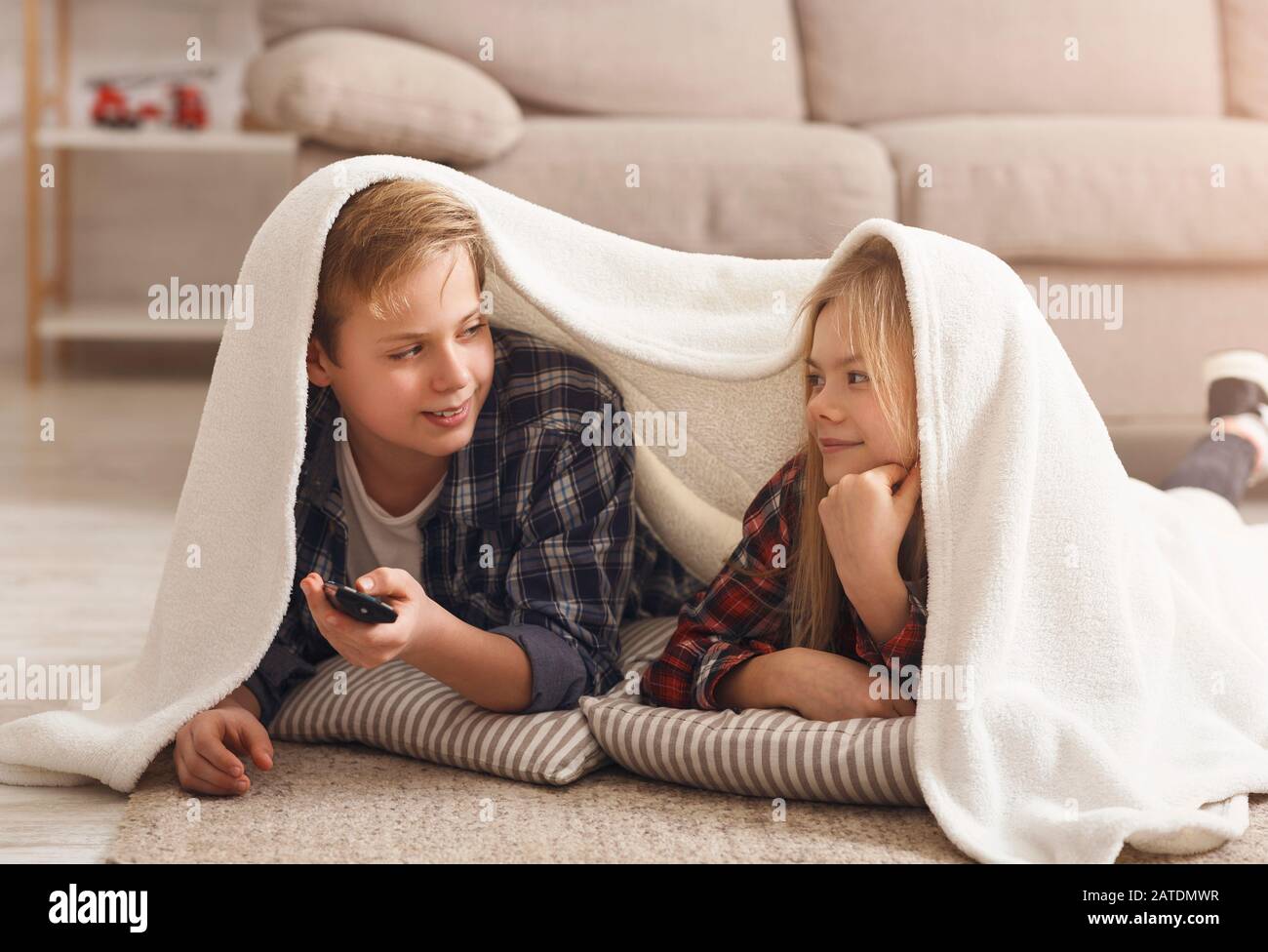 Brother And Sister Watching TV Lying On Floor At Home Stock Photo