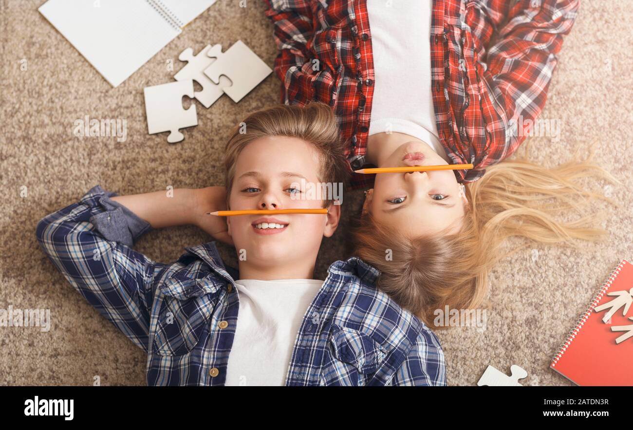 Brother And Sister Lying On Floor Having Fun At Home Stock Photo