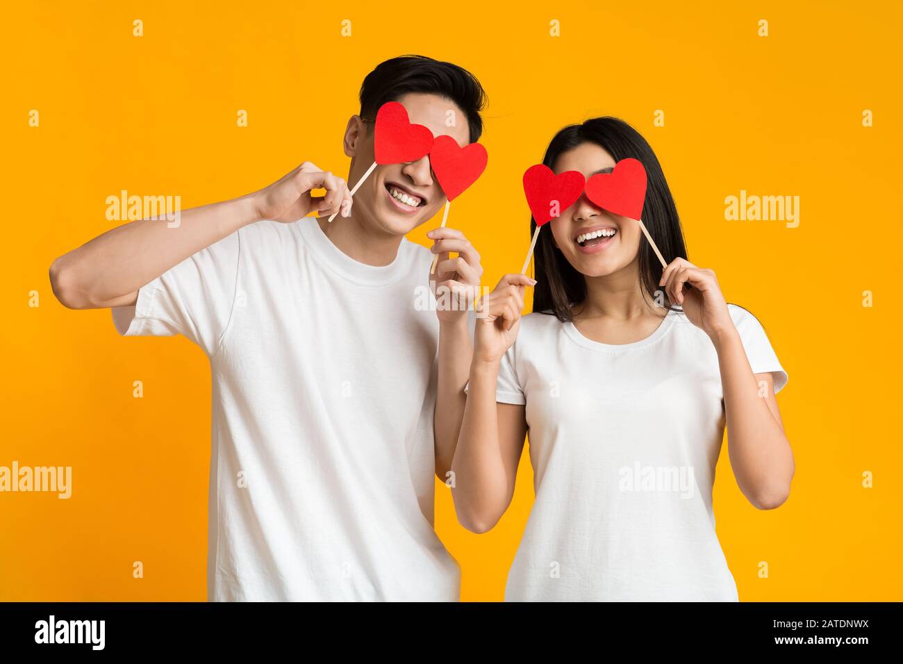 Young asian couple holding red love hearts over eyes Stock Photo